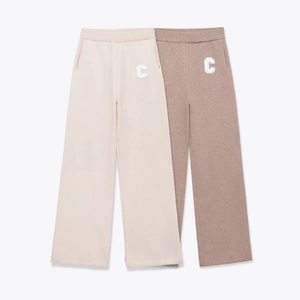 Detail of knit wide-leg track pants with white terry cloth letter C embroidery patch