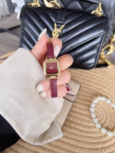 Detailed view of women's vintage square gold watch with burgundy leather strap on wrist