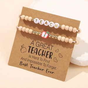 Close-up of TEACH beaded bracelets with wood beads and red apple charm on gift card
