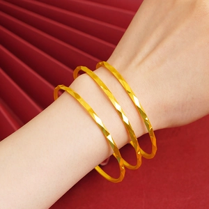 Polished gold rhombus faceted bangles for women displayed on a red fan background