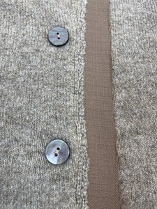 Detail of oatmeal knit cardigan showing textured wool fabric and iridescent dark buttons