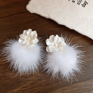 Détail de la boucle d'oreille fleur blanche avec pompon en peluche sur bois noir