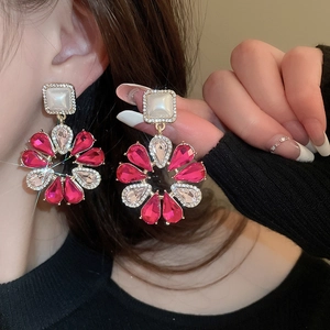 Detail von großen goldenen Blumenohrringen mit rosa Kristallen an einem Model