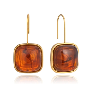 Vue macro de boucles d'oreilles carrées en résine ambre avec crochets dorés et texture