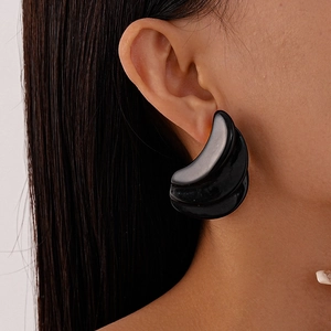 Macro detail of triple-layer black resin geometric stud earrings on model's ear
