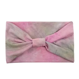 Detail of wide-brimmed tie-dye sports headband with a twisted knot design and pink-green texture