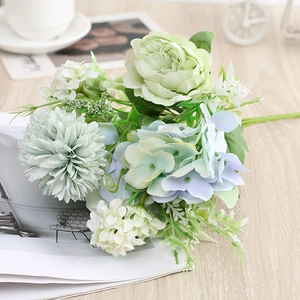 Artificial bouquet with light green and blue roses, hydrangeas, and mums on a wooden table