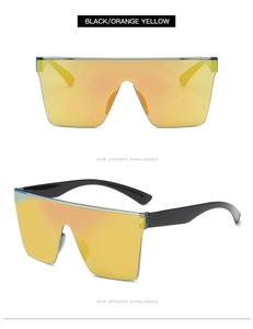 Detail showing oversized black frame sunglasses with orange-yellow reflective mirrored lenses