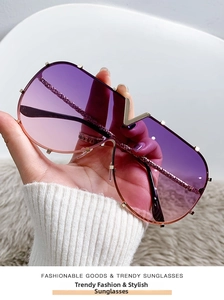 Detail of rimless shield sunglasses featuring gradient purple lenses and a gold V-shape bridge