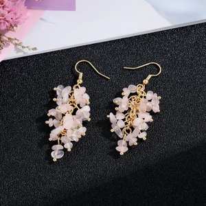 Detail of pink crystal stone tassel earrings with gold hooks on a textured background