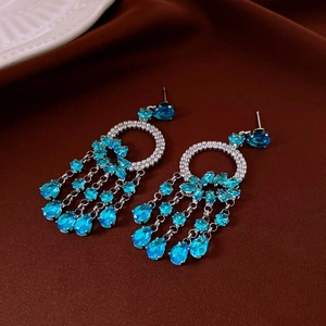 Detail of silver drop tassel earrings with blue teardrop stones and zircon accents