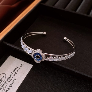 Detail of flower shaped evil eye bangle with sparkling zircons on a black display box