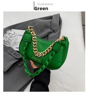 Close-up of bright green underarm bag with chunky gold chain and woven strap detail