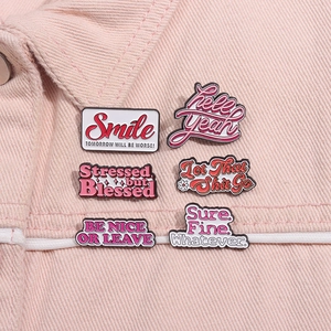 Close-up of funny enamel pins with pink English slogans on a denim jacket