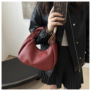Detail of dark red woven leather texture and knot design on crescent shoulder bag