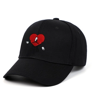 Close-up of black cotton baseball cap featuring unique red heart embroidery with eyes