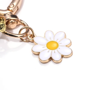 Detailed macro view of white enamel daisy keychain with polished gold hardware plating