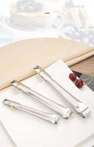 Three-piece stainless steel tongs set with serrated tips on a wooden tabletop