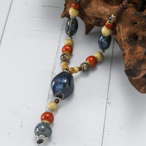 Ethnic style ceramic beaded necklace with colorful stones on a dark wood display