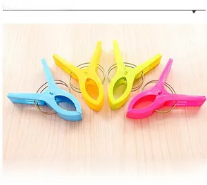 Set of four colorful heavy-duty plastic windproof laundry pegs on a light wood background