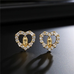 Macro detail of gold-plated heart earrings with clear zircon stones and Virgin Mary relief