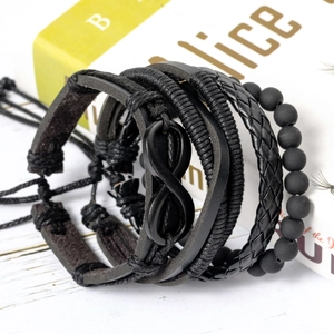 Detail of multi-layer black leather bracelets with infinity charm on white wood surface