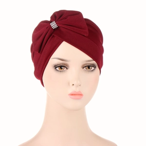 Detail of burgundy turban cap with large bow knot and sparkling rhinestone centerpiece