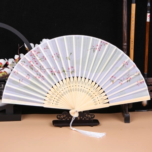 Detail of folding fan showing carved wood ribs and delicate floral silk patterns