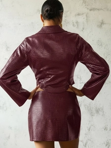 Detailansicht eines Sets aus bordeauxroter PU-Lederjacke mit Krokoprägung und Minirock