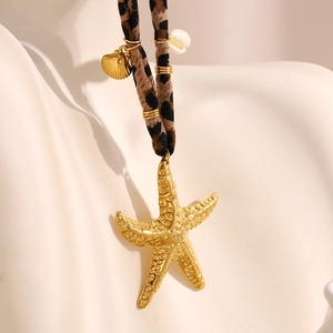 Detailed macro view of 18K gold starfish pendant with leopard print textile cord necklace