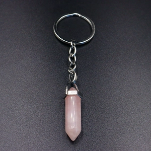 Detail view of a hexagonal rose quartz crystal point pendant attached to a silver keychain