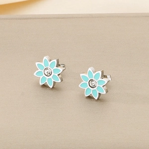Détail macro de boucles d'oreilles lotus argentées avec pétales bleus et zircon central