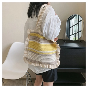 Knitted tote bag with ruffled edges and colorful stripes shown on a model's shoulder
