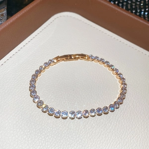 Detail of 18k gold plated tennis bracelet with round cut crystals on leather background