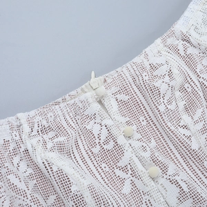 Détail de la robe en dentelle blanche avec fermeture éclair invisible et boutons