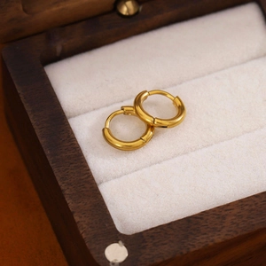 Close-up of minimalist 18K gold-plated stainless steel hoop earrings on white velvet
