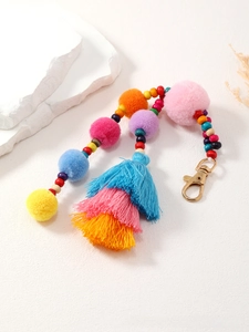 Dettaglio di un portachiavi con pompon colorati, perline in legno e nappe in cotone