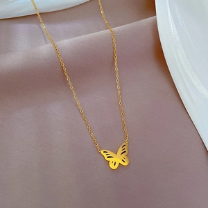 Dettaglio del ciondolo a farfalla dorata traforata su catena in acciaio al titanio