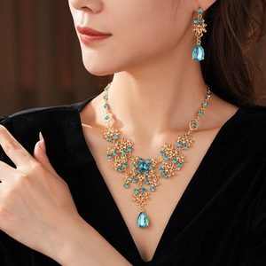 Detail of vintage gold necklace and blue crystal earrings set on a female model