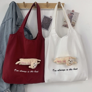 Detail of canvas tote bags with plush 3D cats and elegant embroidery in red and white