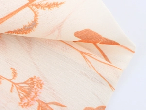Detail eines Blumen-Chiffonkleids mit orangefarbenem Muster und gewebter Stoffstruktur