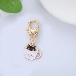 Detailed macro shot of a gold cat in coffee cup enamel keychain with lobster clasp