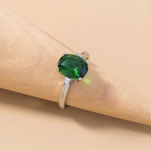 Macro shot of silver ring with oval green gemstone on a wooden cone display stand