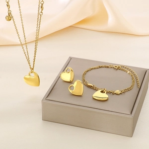 Detailed set of 18K gold plated heart necklace, bracelet and earrings on a silk background
