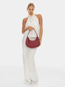 Detail of burgundy leather crescent hobo bag with slim strap on white outfit