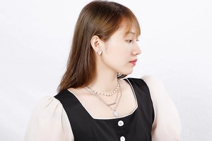 Model wearing a multi-layered silver necklace with pearl beads and heart earrings