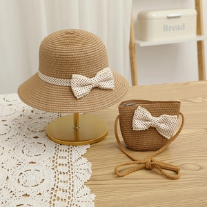 Close-up of children's straw hat and matching bag set with lace dot bow decoration