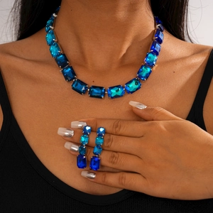 Detail of blue rectangular gemstone necklace and matching earrings worn by a model