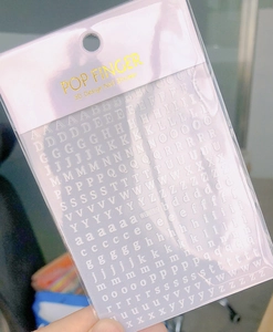 Detailed close-up of white 3D gothic letter nail stickers in protective packaging