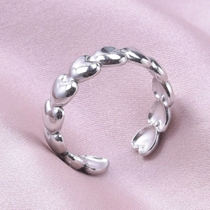 Macro shot of silver heart-link stainless steel twisted ring on pink silk fabric